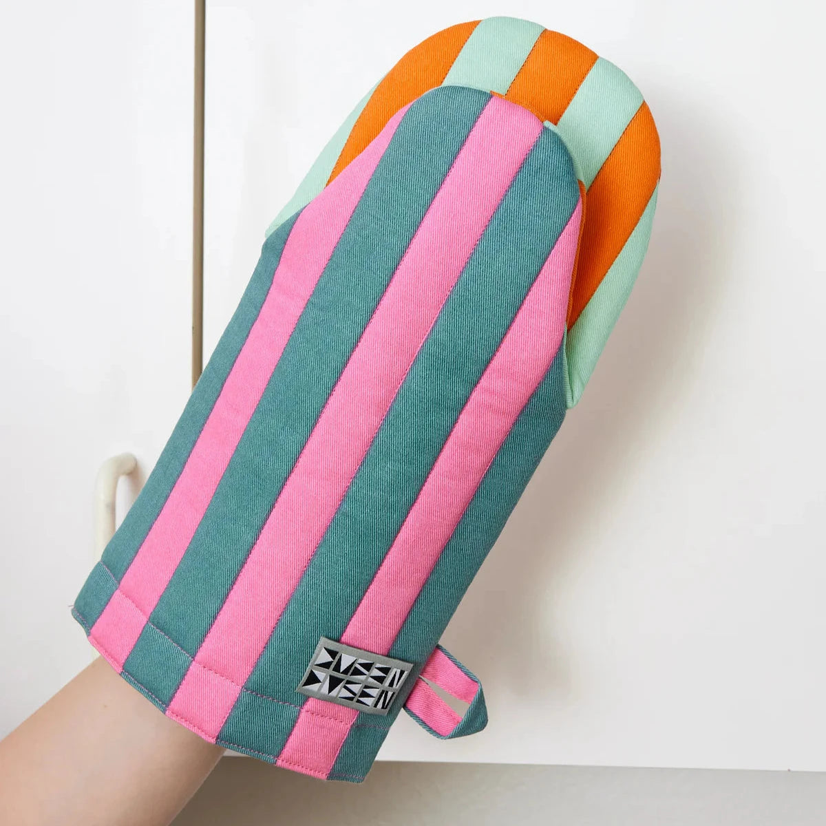 Ginger Oven Mitt by Dusen Dusen – a close-up of the mitt in use, highlighting the pink and teal striped pattern with an orange and mint reverse.