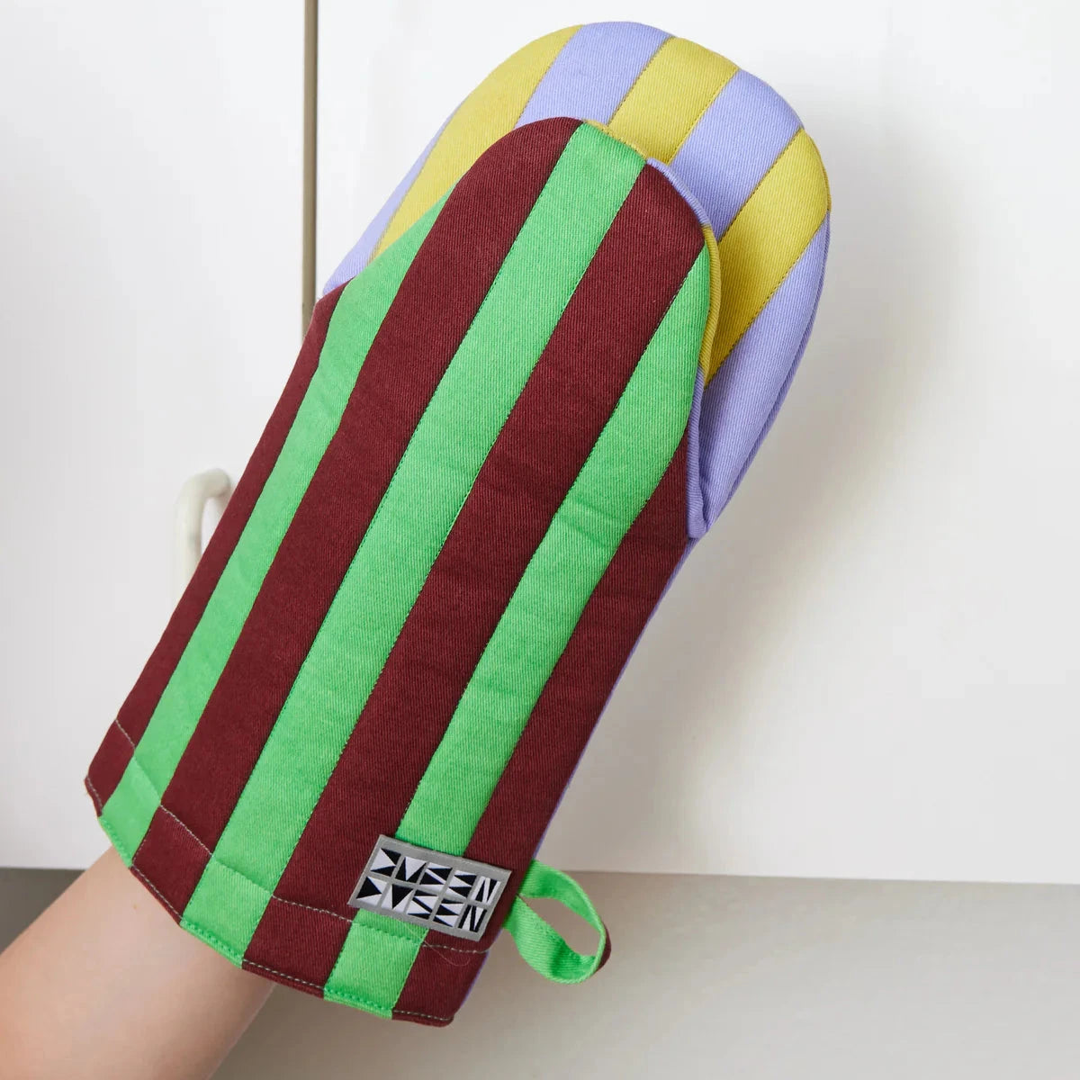 Jalapeño Oven Mitt by Dusen Dusen – close-up of the mitt in use, highlighting green and burgundy stripes on one side and lavender with yellow stripes on the reverse.