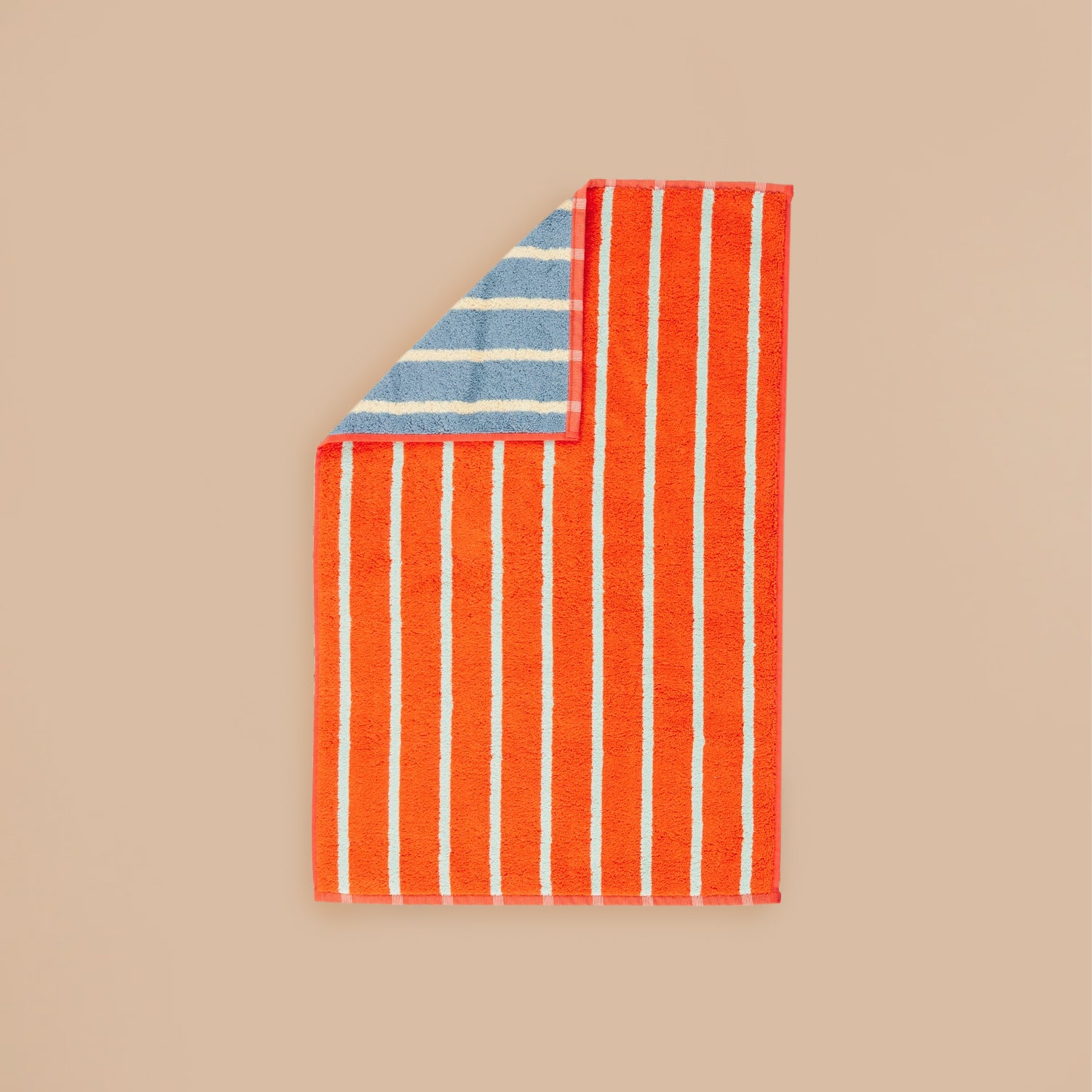 Stone Stripe Hand Towel by Dusen Dusen – an orange towel with light blue stripes on one side and blue with cream stripes on the reverse, displayed flat on a beige background.