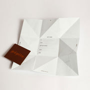 Fully opened pépite gift card featuring an origami-inspired geometric fold, with sections for to/from details and a separate brown card with the 'pépite' logo.