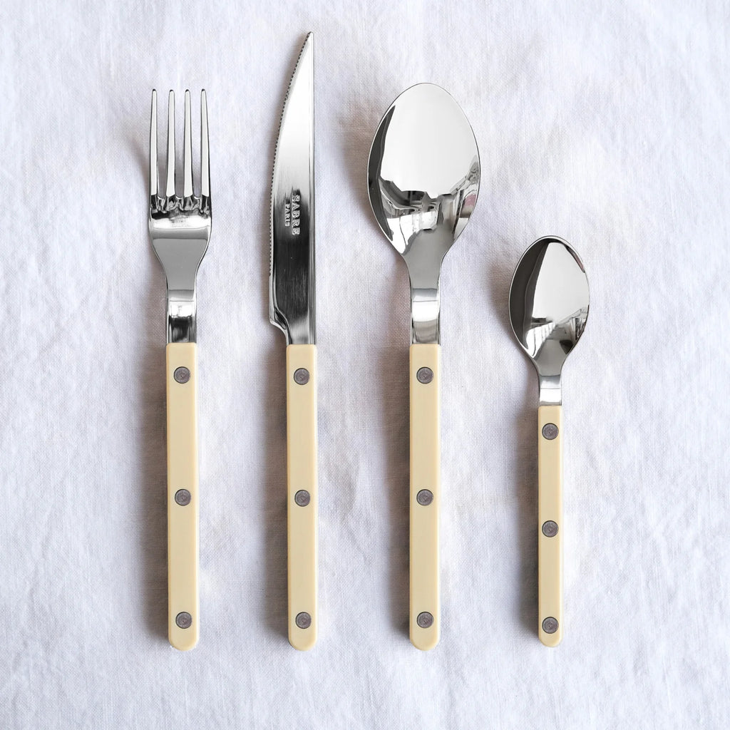 Elegant Sabre Paris Bistrot Solid cutlery set in Ivory, displayed on crisp white fabric, showcasing the sleek and minimal design.