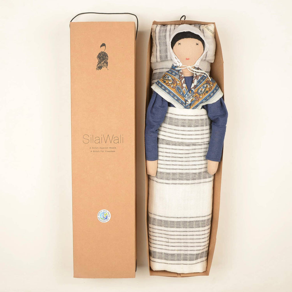Jeanne doll by SilaiWali packaged in a cardboard box, wearing a vibrant patterned dress and headscarf.