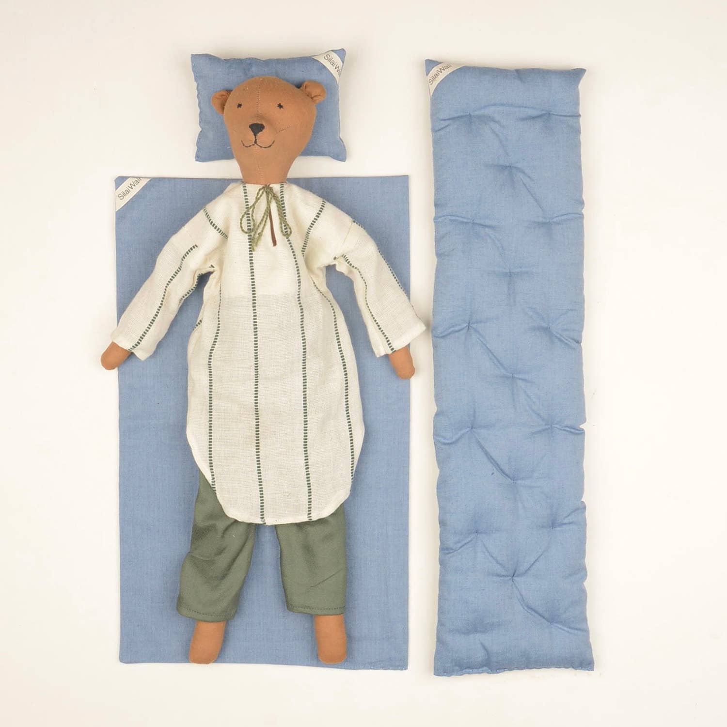 Voda the Bear doll by SilaiWali displayed with a bedding set, featuring blue fabric and a stitched tunic.