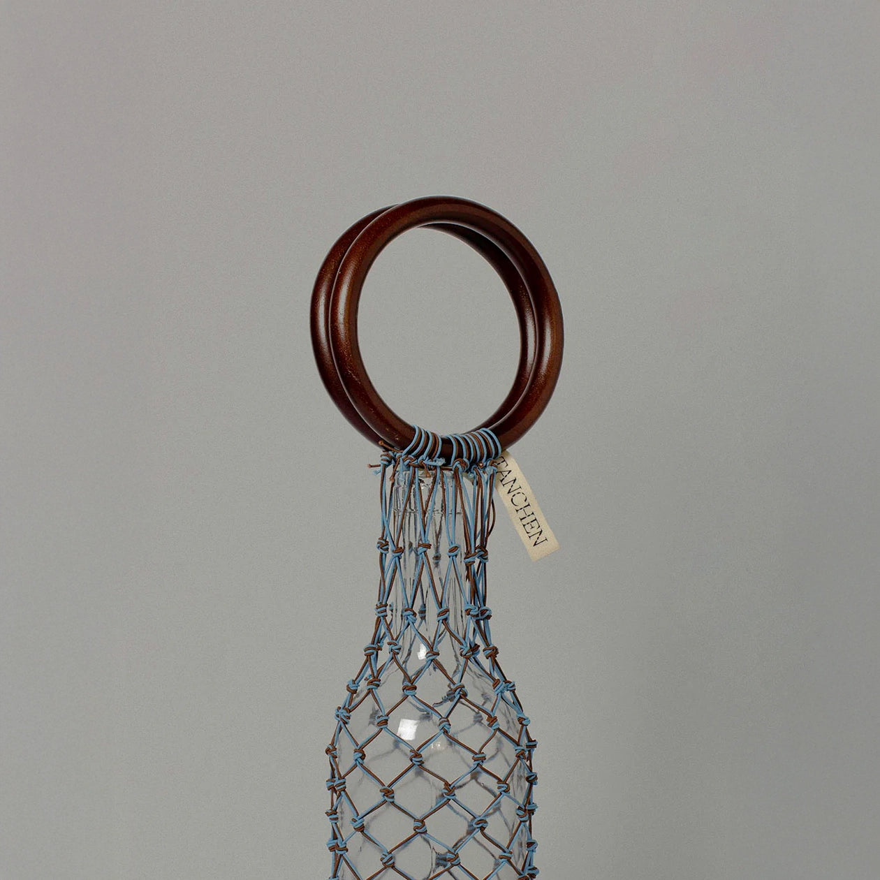 Close-up detail shot of the 00 Bag in Blue Brown by Tanchen, highlighting the craftsmanship of the woven netting and branded tag.