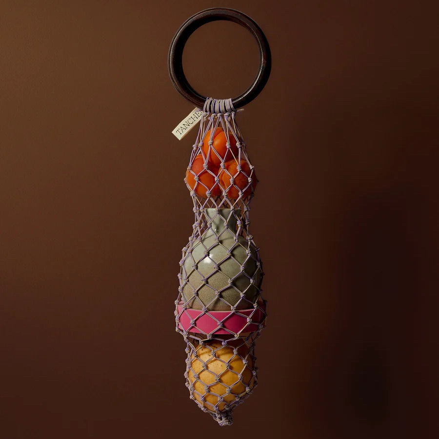 Tanchen 0/0 Bag in Lilac Sand holding fruit with wooden ring, showcasing a unique woven net design.