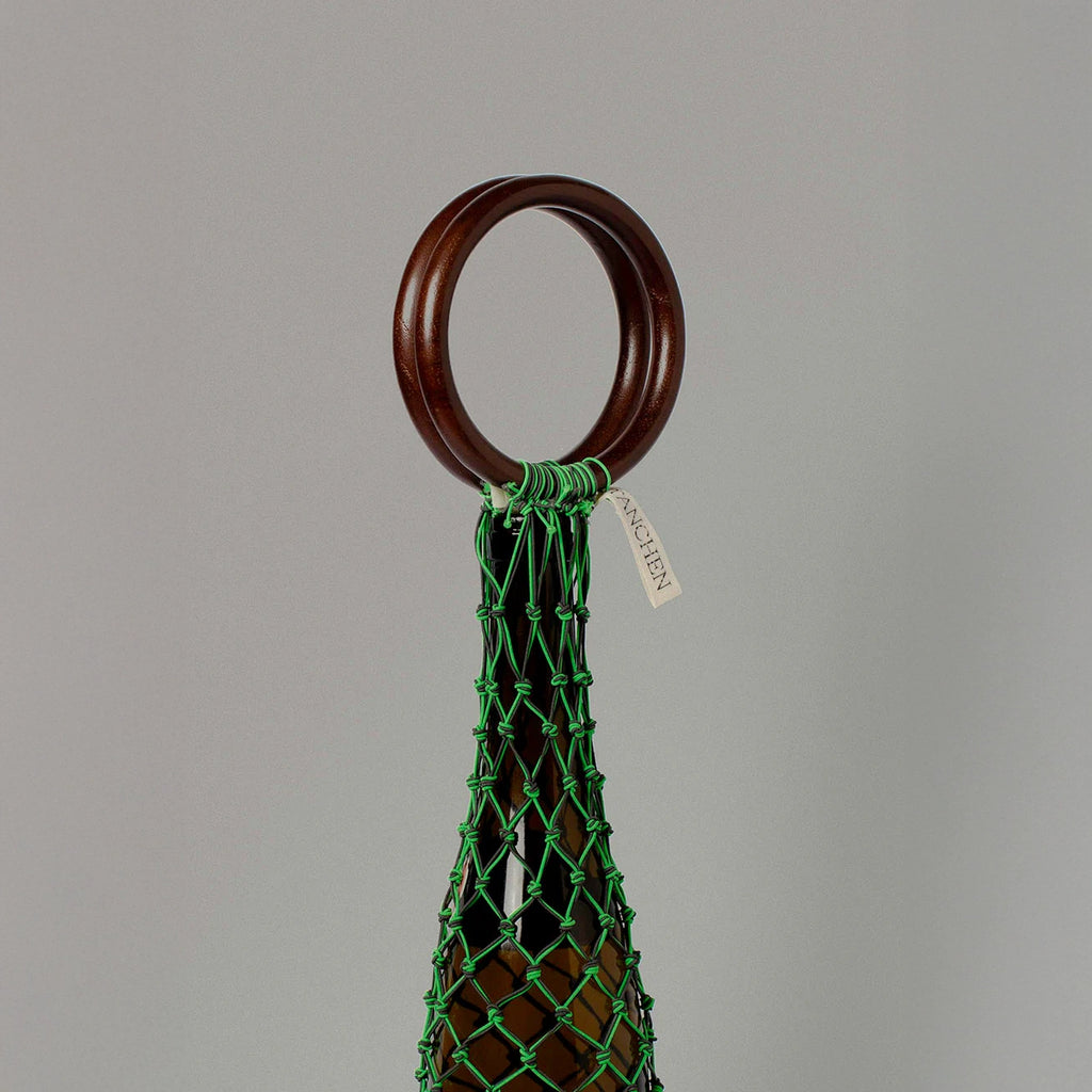 Close-up detail shot of the 0/0 Bag in Neon Green Black by Tanchen, highlighting the vibrant green netting, wooden ring handle, and branded tag.