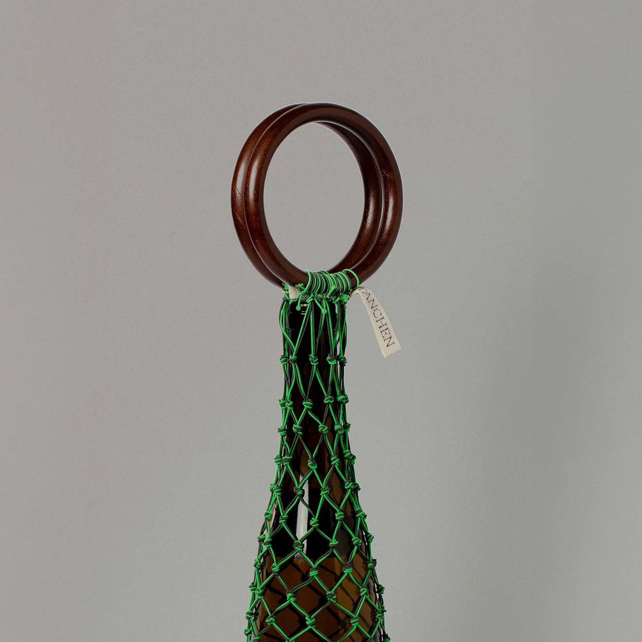 Close-up detail shot of the 0/0 Bag in Neon Green Black by Tanchen, highlighting the vibrant green netting, wooden ring handle, and branded tag.