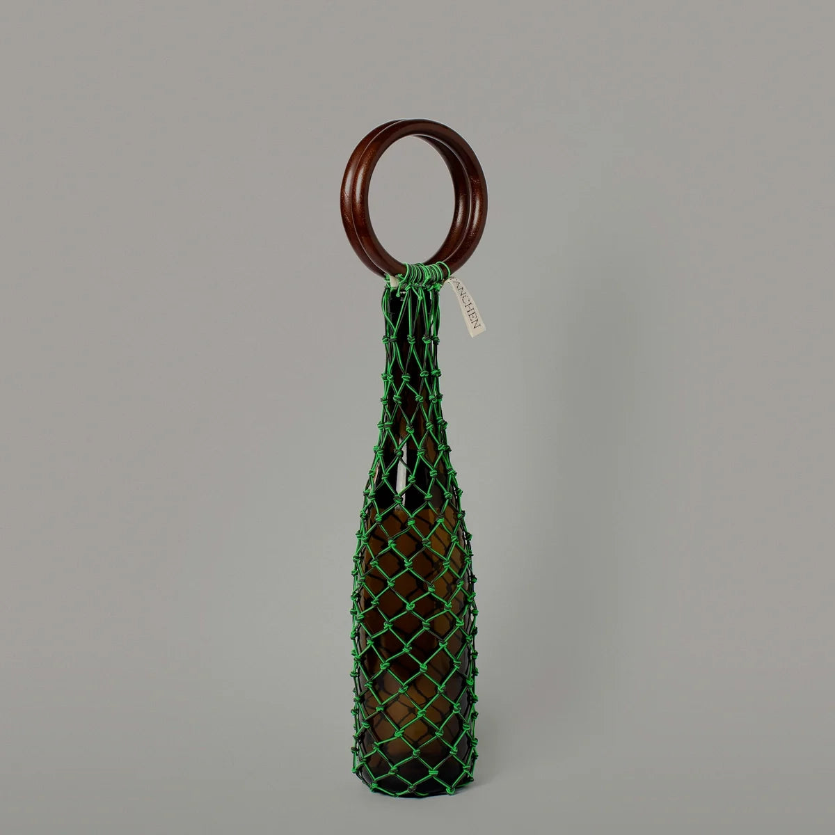 Front view of the 0/0 Bag in Neon Green Black by Tanchen, featuring the neon green netting and sleek wooden ring handle.