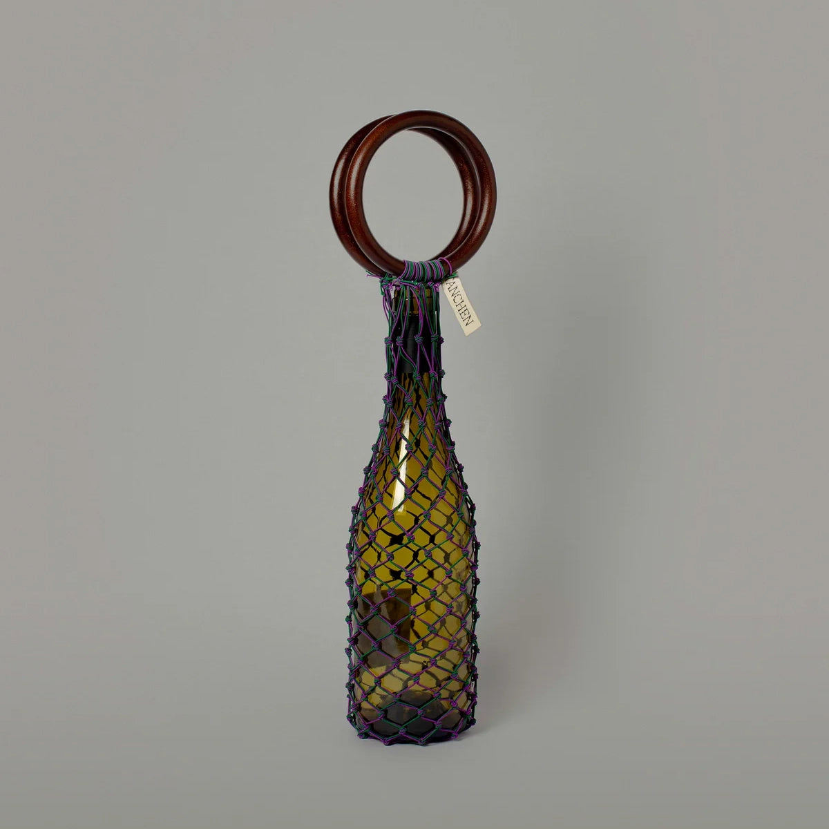 Front view of the 0/0 Bag in Purple Green by Tanchen, featuring a vibrant purple and green netting design with a wooden ring handle.