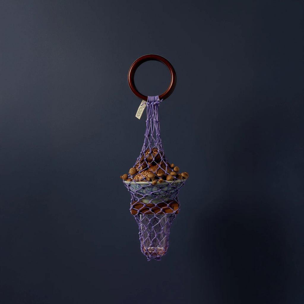 Styled image of the 0/0 Bag in Purple Lilac by Tanchen, featuring a unique design holding decorative elements against a dark blue background.