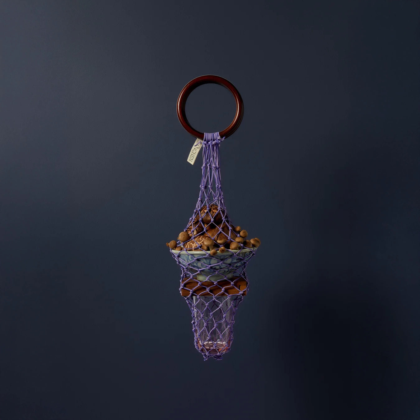 Styled image of the 0/0 Bag in Purple Lilac by Tanchen, featuring a unique design holding decorative elements against a dark blue background.