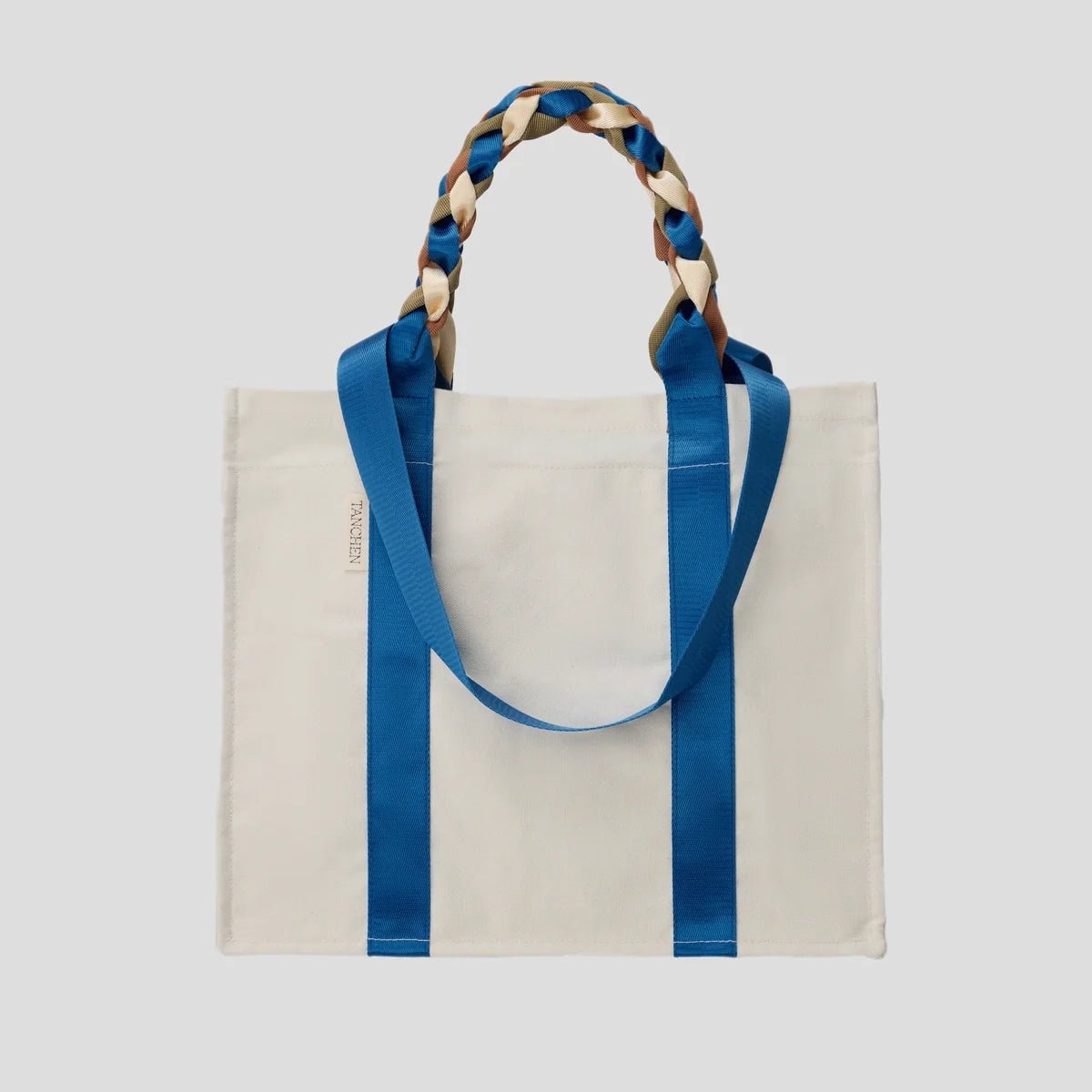 Front view of the Picnic Bag Glou! by Tanchen, showcasing its cream cotton canvas and vibrant blue and brown nylon ribbon handles.