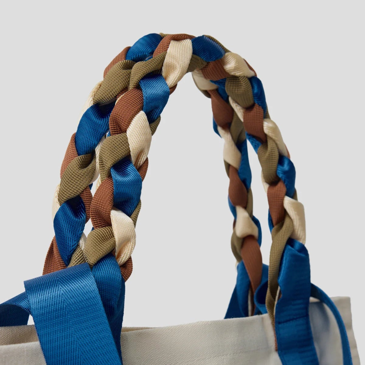 Close-up of the braided blue, brown, and cream nylon ribbon handles of the Picnic Bag Glou! by Tanchen, showcasing its elegant craftsmanship.