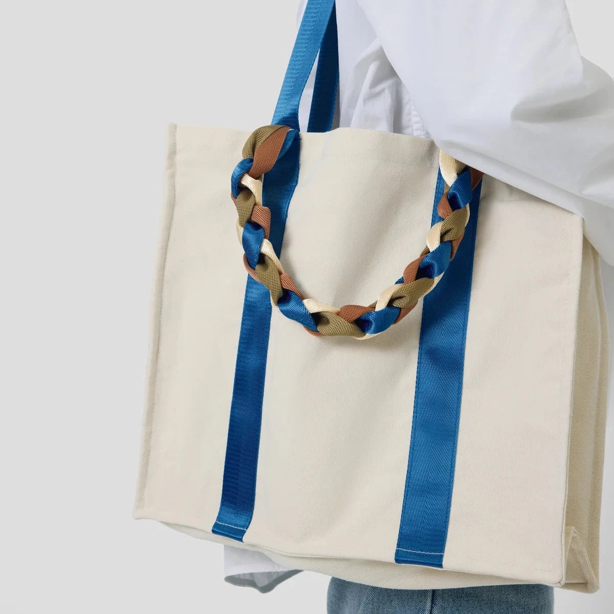 Picnic Bag Glou! by Tanchen, worn on the shoulder to display its functional size and striking blue ribbon accents.