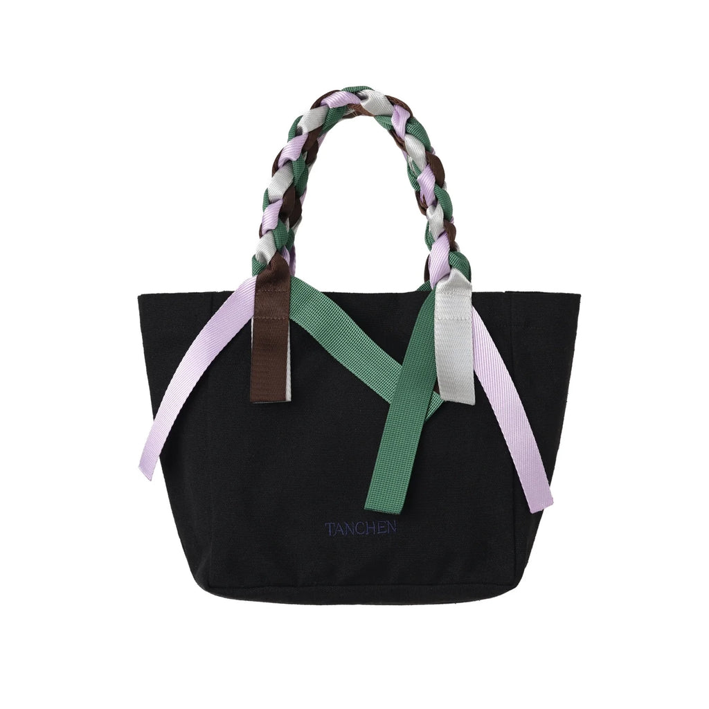 Front view of the Picnic Bag Mini Shrub by Tanchen, highlighting its black cotton canvas, braided handles, and colourful ribbon details.