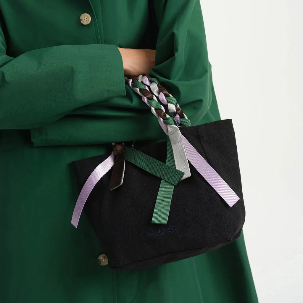 Styled image of the Picnic Bag Mini Shrub by Tanchen, carried by a model wearing a green coat to highlight the bag's compact and elegant design.