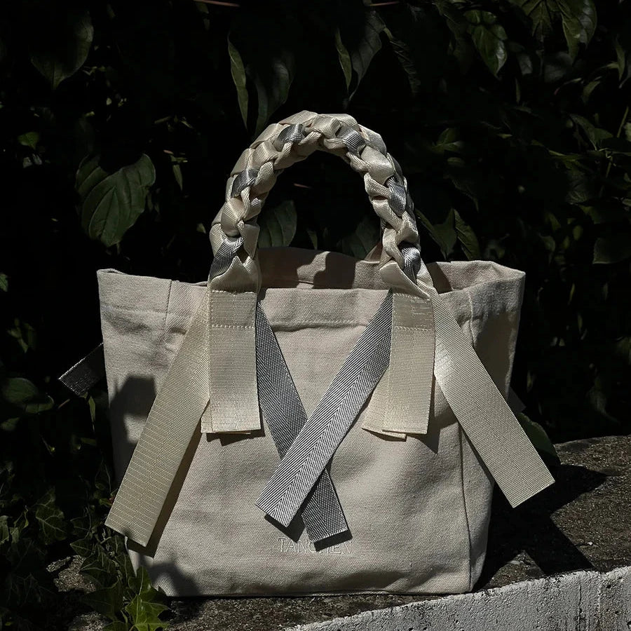 Lifestyle shot of the Tanchen Picnic Bag Mini Soda in cream and silver, styled in a casual outdoor setting. The bag is paired with natural surroundings, showing its versatility as an accessory.