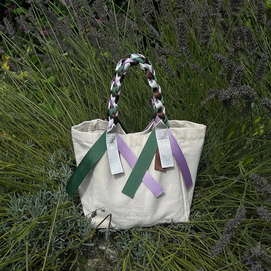 Tanchen Picnic Bag Mini Spritz in cream and multi-coloured ribbons placed amongst lavender bushes.
