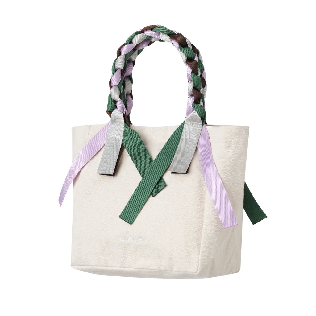 Side view of the Tanchen Picnic Bag Mini Spritz in cream cotton canvas with braided multi-coloured nylon ribbon handles and decorative accents.